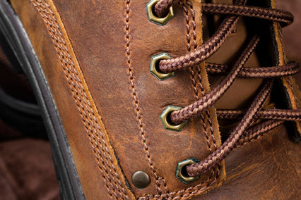 Detailed close-up of brown leather shoe with focus on shoelace and stitching.
