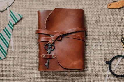 A stylish leather journal with vintage key on burlap, perfect for writers.