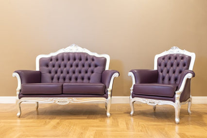 Elegant vintage-style sofa and chair with tufted leather upholstery on a wooden floor.